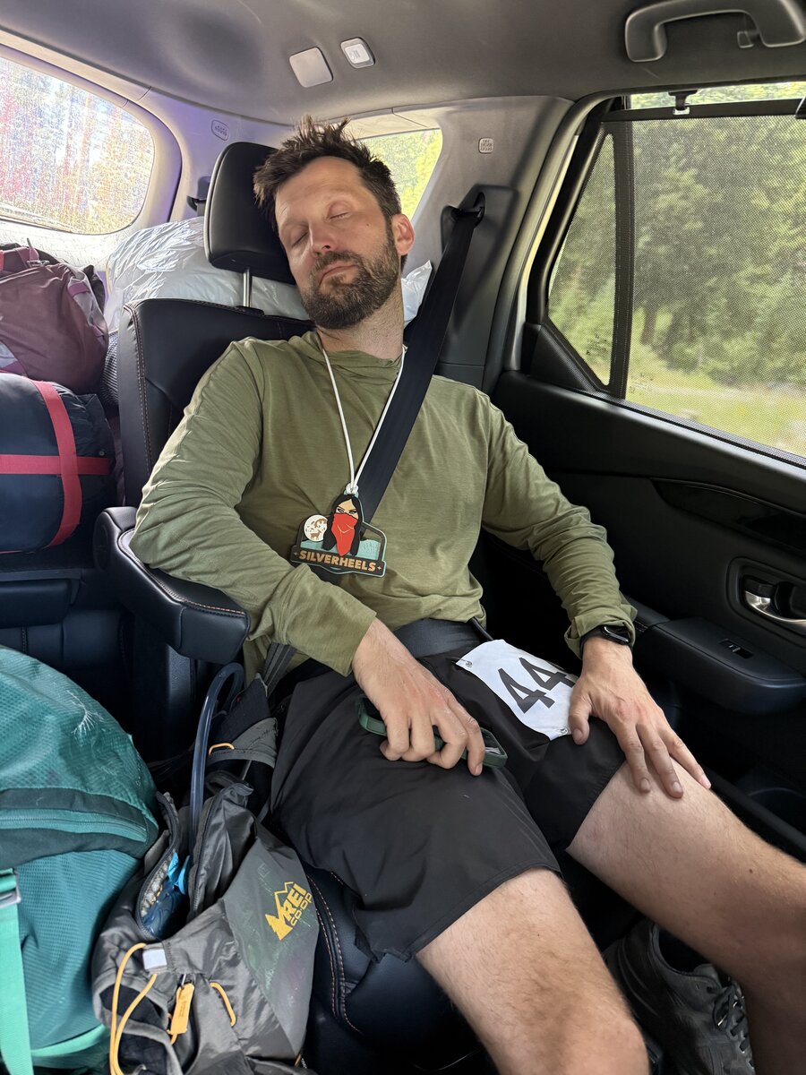 Jon Juleus asleep in the car after finishing the Silverheels 50-mile ultramarathon, still wearing his finisher medal and bib number